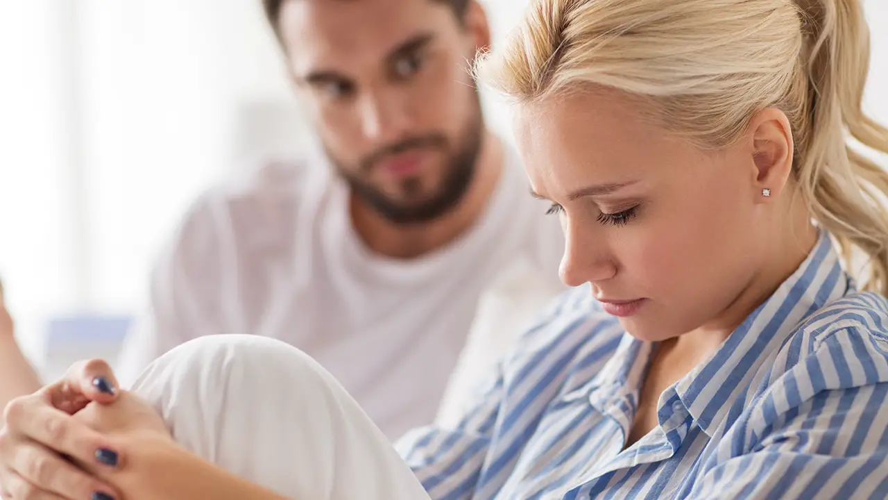 A worried woman sitting next to her husband A worried woman sitting next to her husband